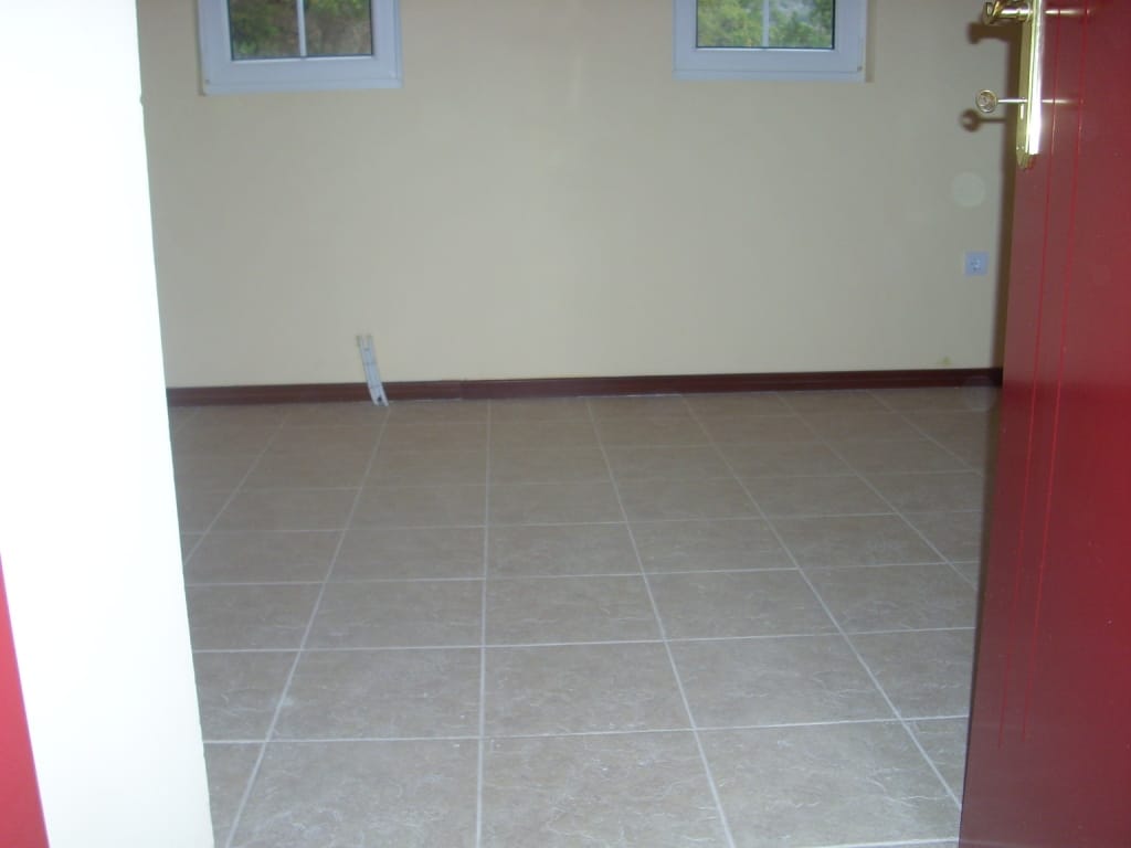 Bright living room with tiled floor in a villa in Markovichi, Montenegro: view of an empty room with two windows.