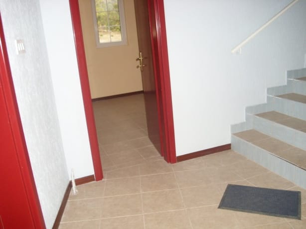 Villa interior in Markovichi, Montenegro: a bright hallway with stairs, tiled floor, and contrasting doorways.