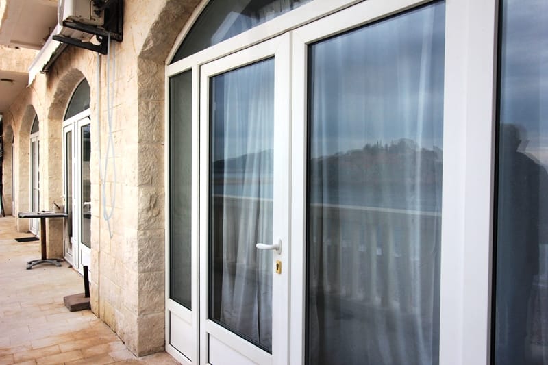 Terrace with stone finishes and panoramic windows in an apartment in Sveti Stefan, Montenegro, with sea and island views.