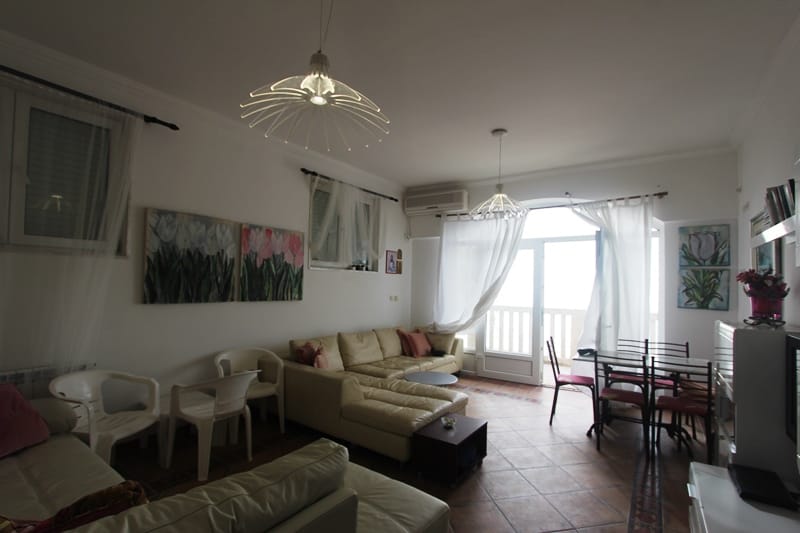 Living room with a leather sofa and access to the terrace in an apartment, Sveti Stefan, Montenegro. Bright interior with sea view.