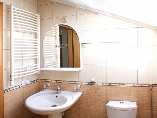 Badezimmer in einer Wohnung in Zelenika, Montenegro: beige Fliesen, Waschbecken, Spiegel und Handtuchheizkörper im Dachgeschoss.