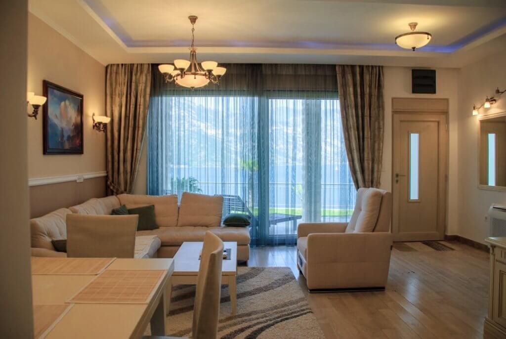 Salon confortable avec mobilier moelleux et vue sur la mer dans un appartement à Kostanica, Monténégro. Intérieur moderne avec terrasse.