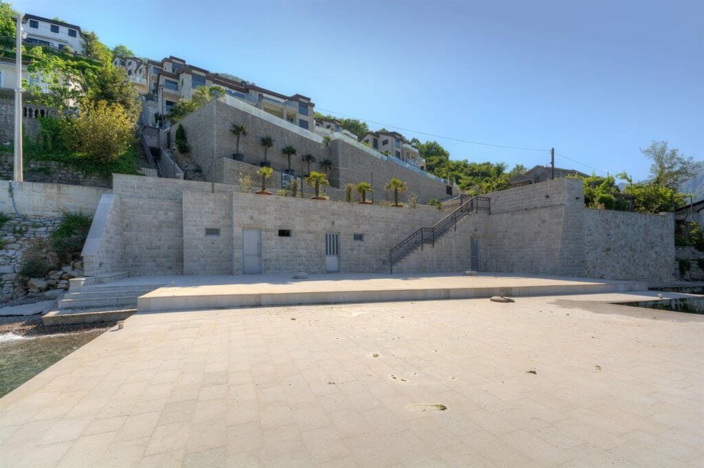 Prywatny kamienny taras nad morzem ze schodami i widokiem na wille w Kostanjicy, Czarnogóra.