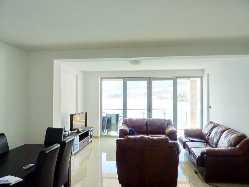 Гостиная с кожаной мебелью и панорамным видом на море в квартире в Рафаиловичах, Черногория.