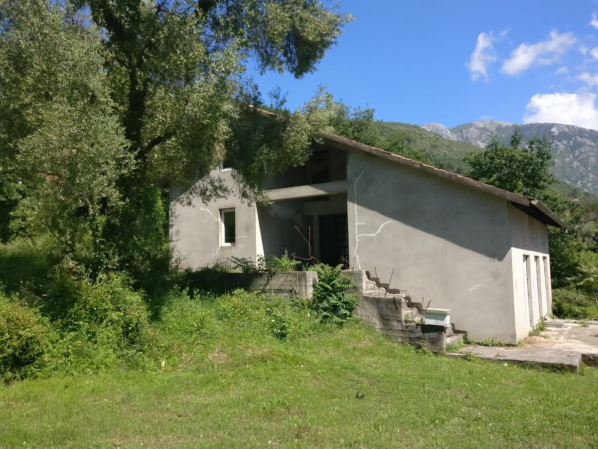 Двухэтажный дом под отделку в Кавачи, Черногория: бетонная конструкция, черепичная крыша и вид на горы.