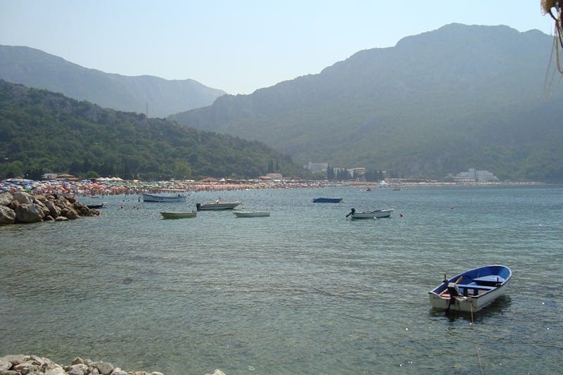 Karadağ, Çanj'daki otelin deniz ve plaj manzarası: güneşli bir günde tekneler, dağ manzarası ve tatilcilerle dolu sahil.