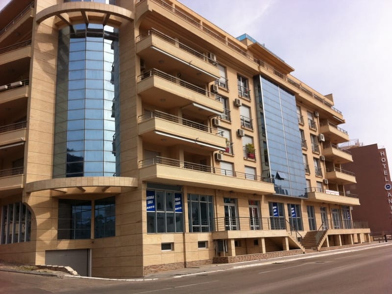 Современный жилой комплекс с панорамным остеклением и балконами в Бечичи, Черногория — фасад здания с коммерческими помеще...