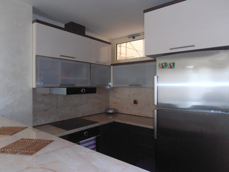 Современная кухня в квартире в Будве, Черногория: белый гарнитур, встроенная техника Gorenje и мраморная столешница.