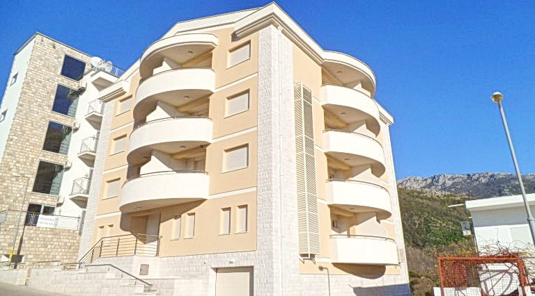 Moderner Wohnkomplex mit halbrunden Balkonen in Bečići, Montenegro: Blick auf die Fassade des Hotels Nr. 227 und die Berge.