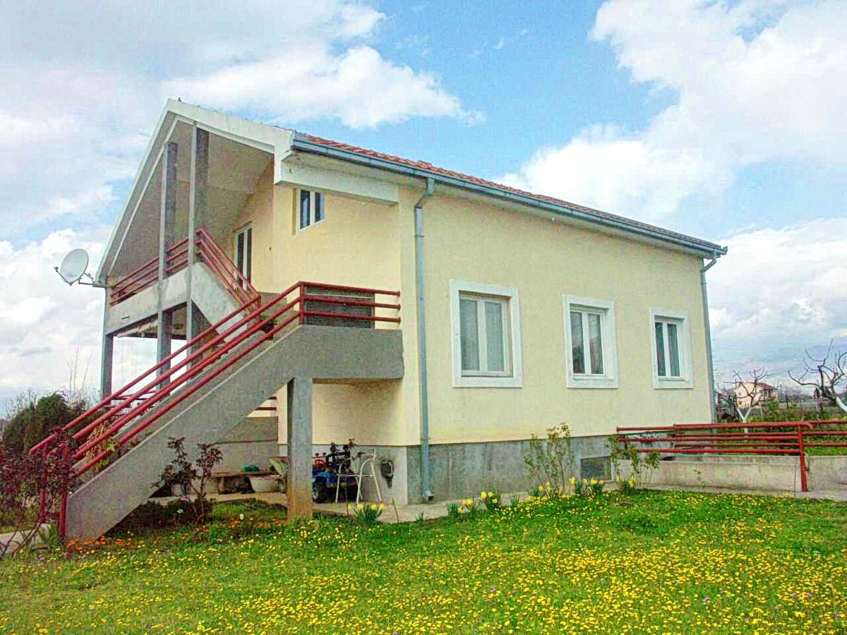 Maison individuelle à deux étages avec escalier extérieur et jardin verdoyant à Podgorica, Monténégro. Vente immobilière.