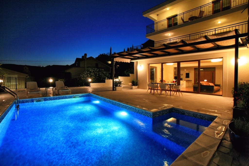 Вечерняя вилла с бассейном и террасой в Герцег-Нови, Черногория: современный дом с подсветкой и зоной отдыха.