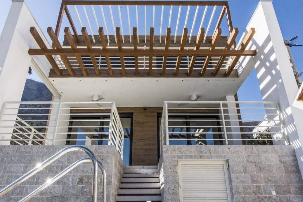 Moderne Villa in Stoliv, Montenegro: Steinverkleidung, Terrasse mit hölzerner Pergola und Treppe zum Pool.