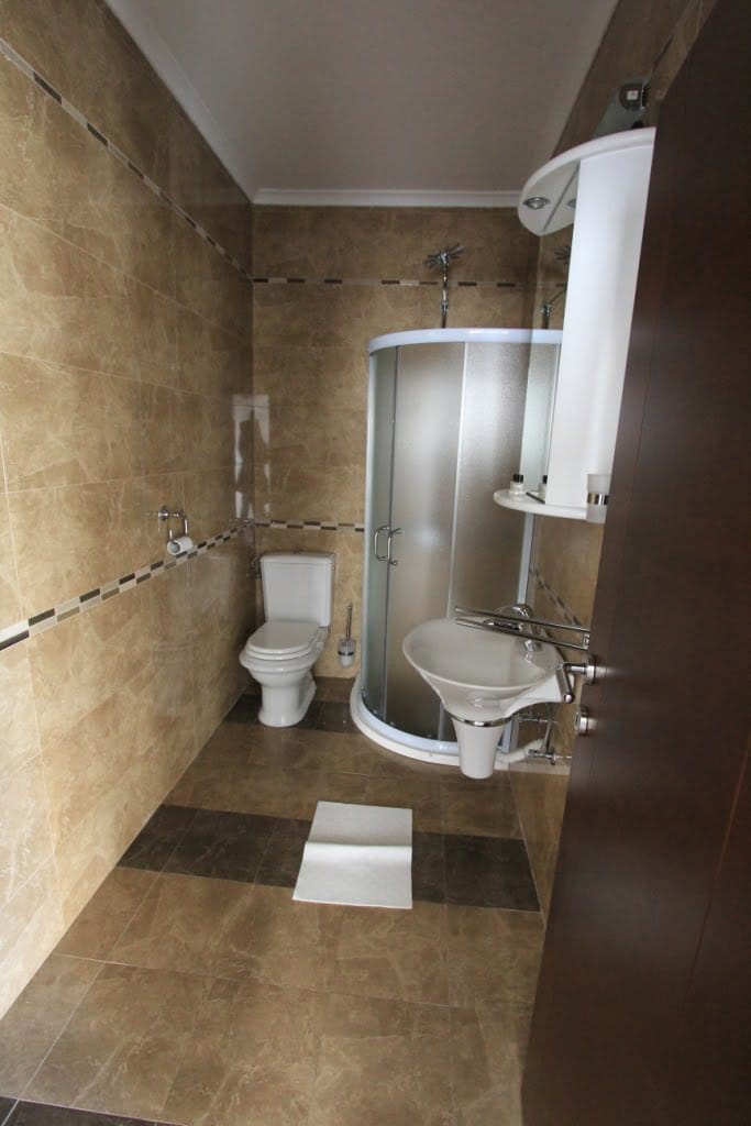 Bathroom with shower cabin in a mini-hotel, Orahovac, Montenegro: marble-look tile finish, plumbing fixtures.