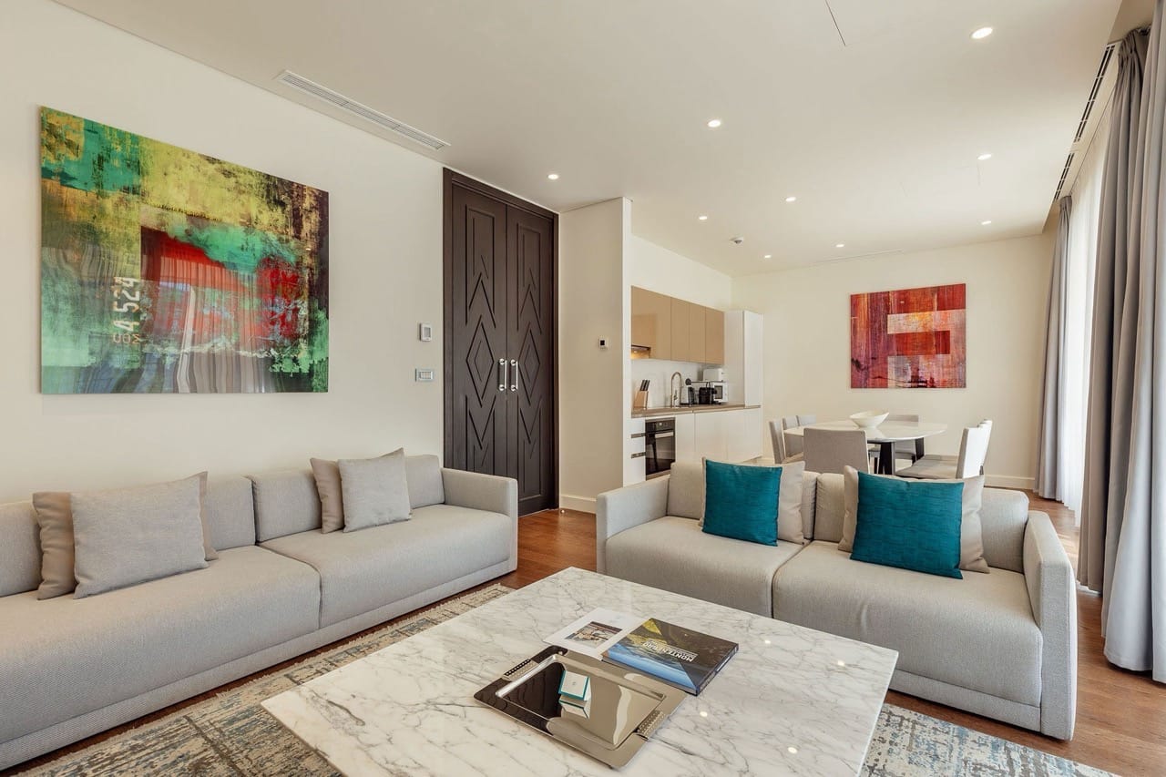 Modern living room with kitchen in Portonovi apartments, Kumbor, Montenegro: light furniture, marble table, and decor.