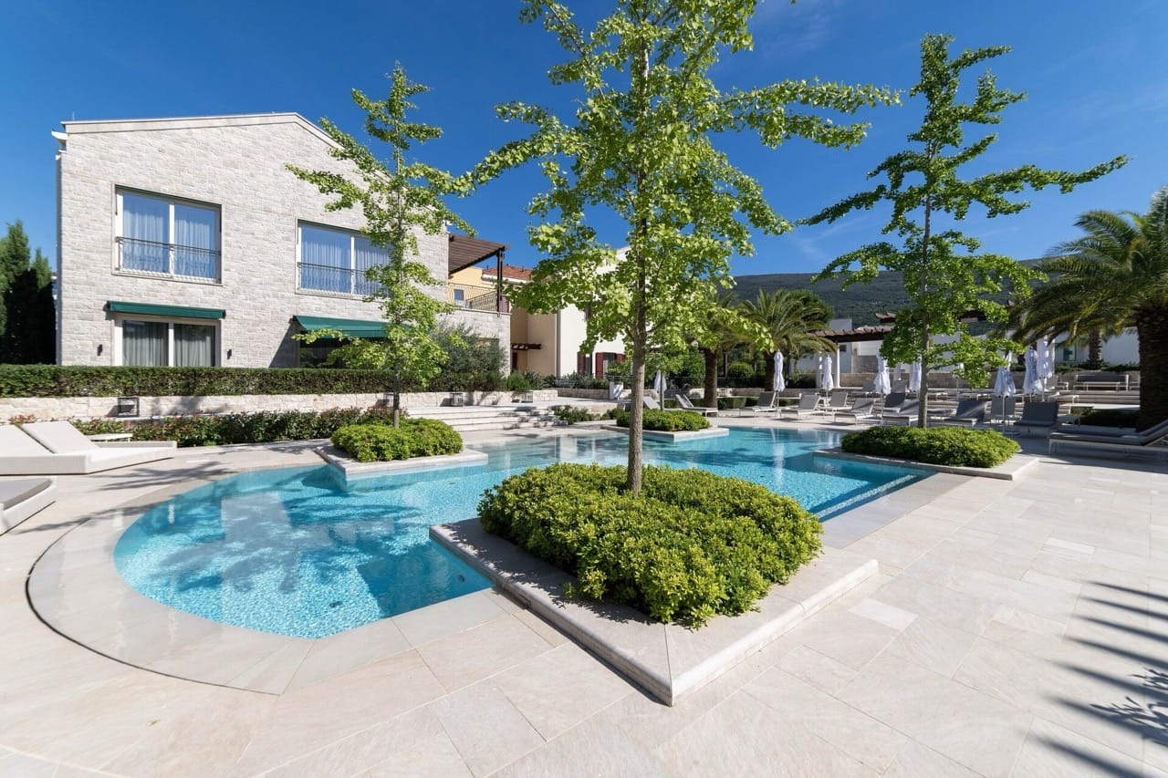 An outdoor pool with landscaping and sun loungers at the Portonovi residential complex, Kumbor, Montenegro.
