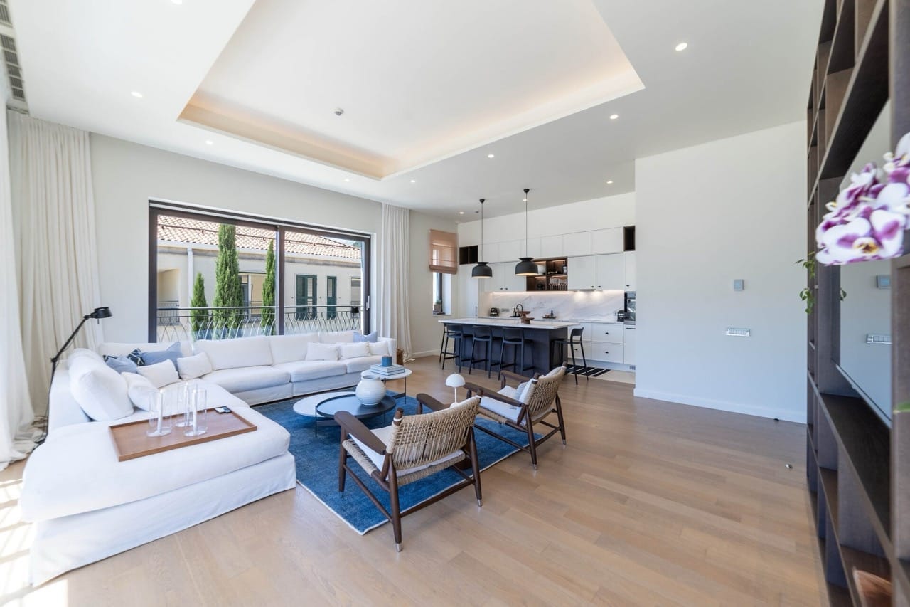 Modern living room with kitchen in an apartment in Portonovi, Kumbor, Montenegro: white sofa, panoramic windows, and stylish decor.
