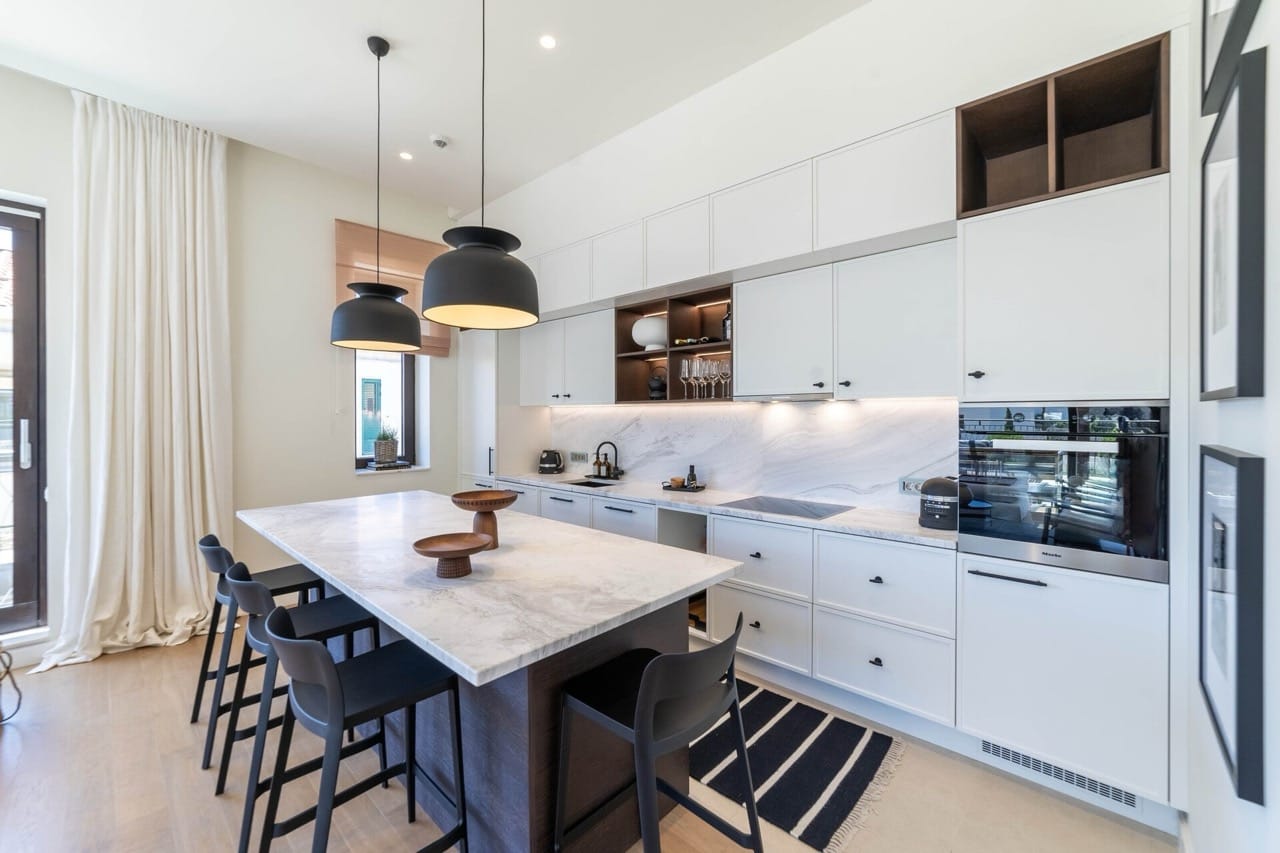 Modern kitchen with an island in an apartment in Portonovi, Kumbor, Montenegro: white cabinetry, marble countertop, and appliances.