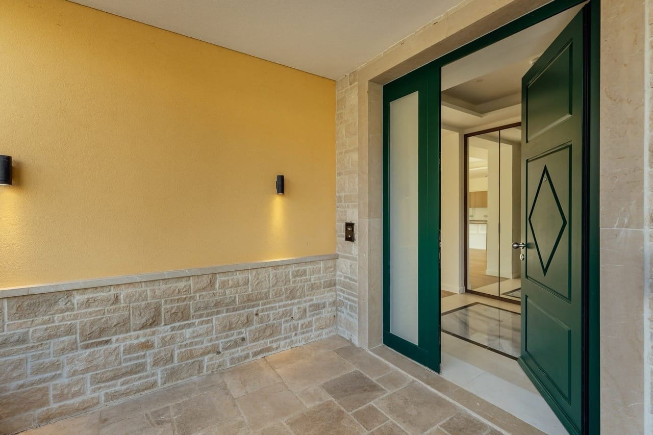 Entrance to the Portonovi villa in Kumbor, Montenegro: green door, stone facade finish, and stylish lighting.