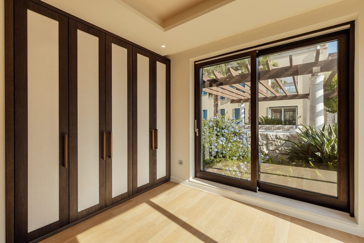 Bedroom with a panoramic window and built-in wardrobe in a villa in Portonovi, Kumbor, Montenegro: modern interior.