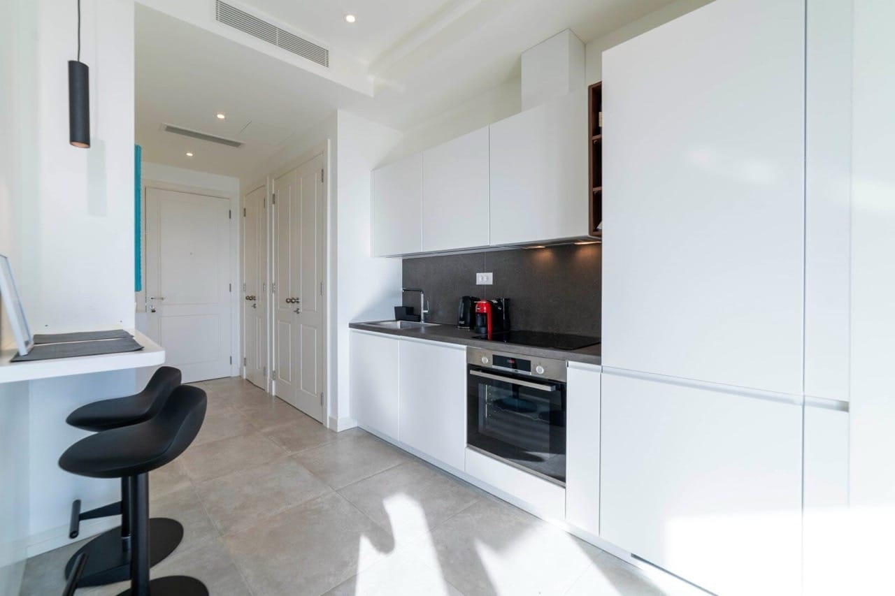 Moderne weiße Küche in der Wohnung Lustica Bay, Radovici, Montenegro: Einbaugeräte und Bartheke.