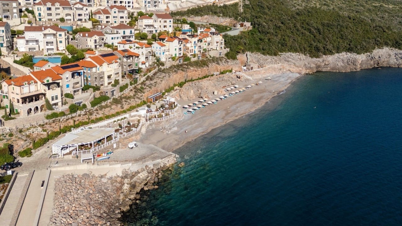 Luftaufnahme des Wohnkomplexes Lustica Bay in Radovici, Montenegro: Privatstrand, Uferpromenade und Küstenlinie.
