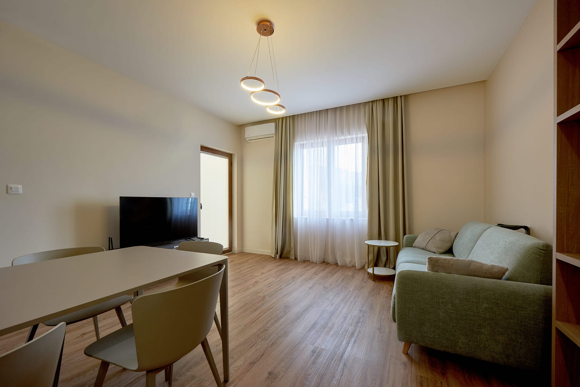 Nowoczesny salon z jadalnią i sofą w apartamencie w Bečići, Czarnogóra. Jasne wnętrze ze strefą telewizyjną.