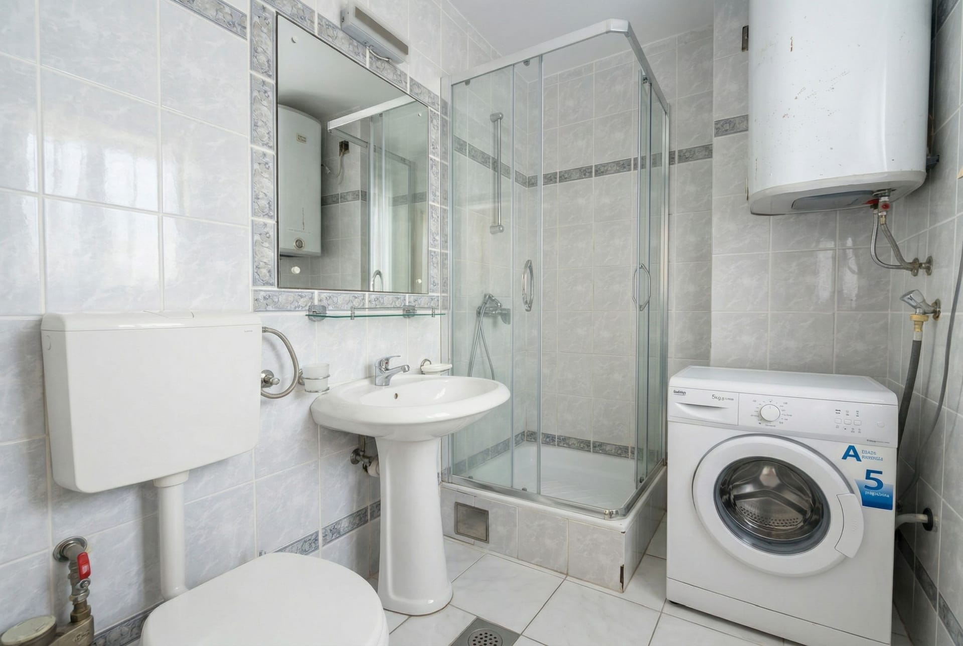 Bathroom in an apartment in Sveti Stefan, Montenegro: shower cabin, sink, toilet, and washing machine.