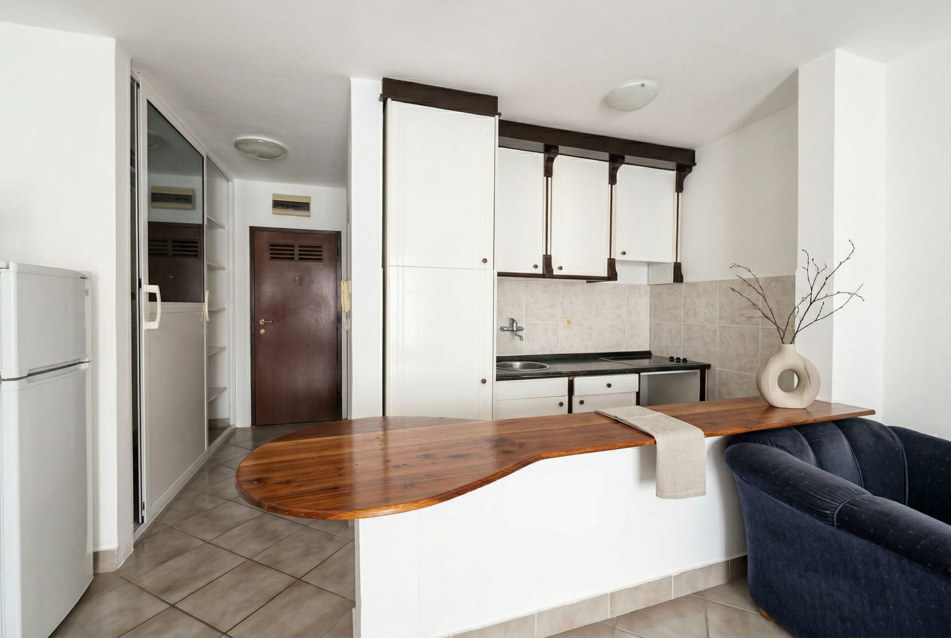 Kitchen with a wooden bar counter and white cabinetry in an apartment in the resort of Sveti Stefan, Montenegro.