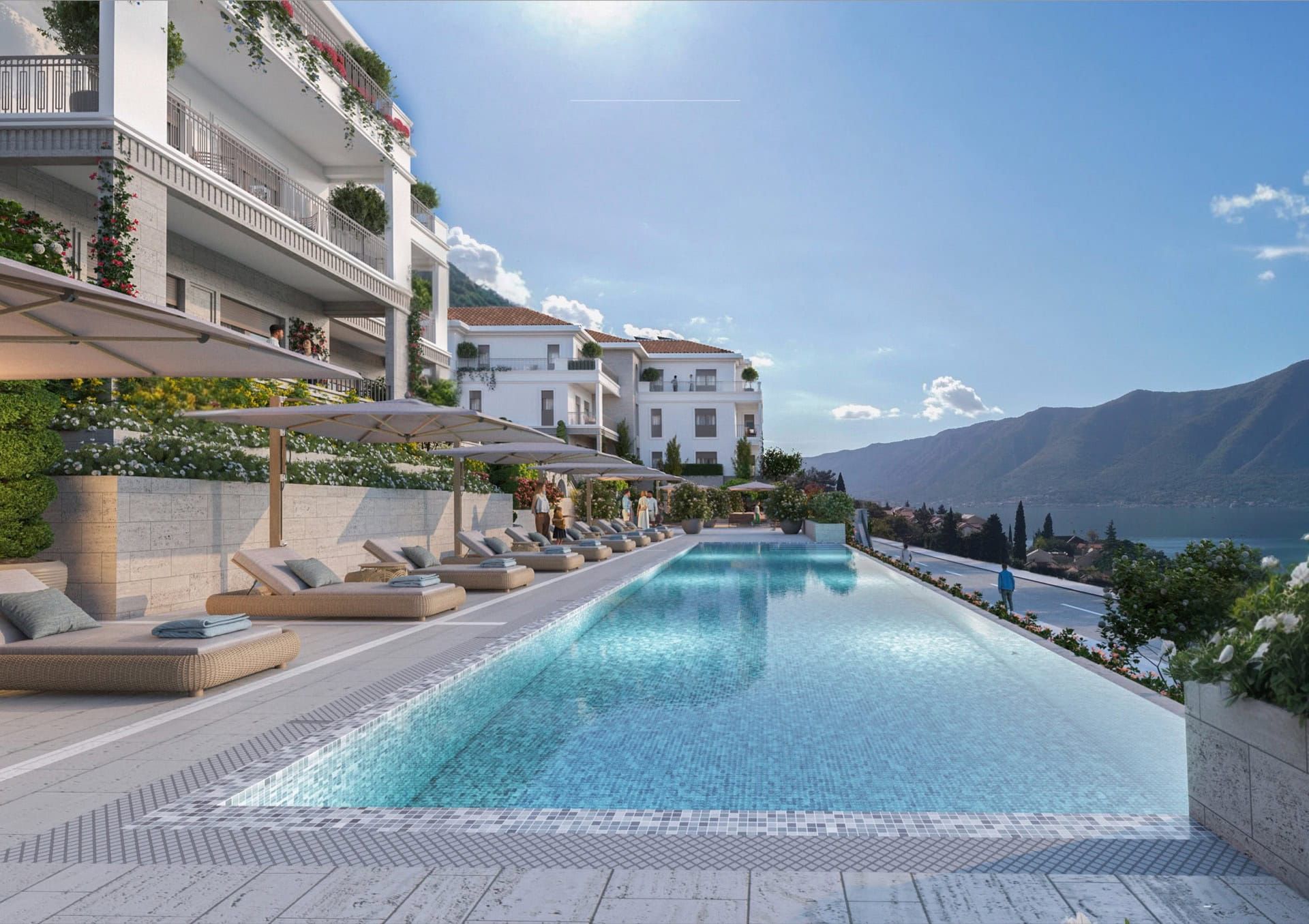 Piscine extérieure avec chaises longues dans un complexe résidentiel haut de gamme à Luštica, Monténégro, avec vue sur les montagnes et la mer Adriatique.