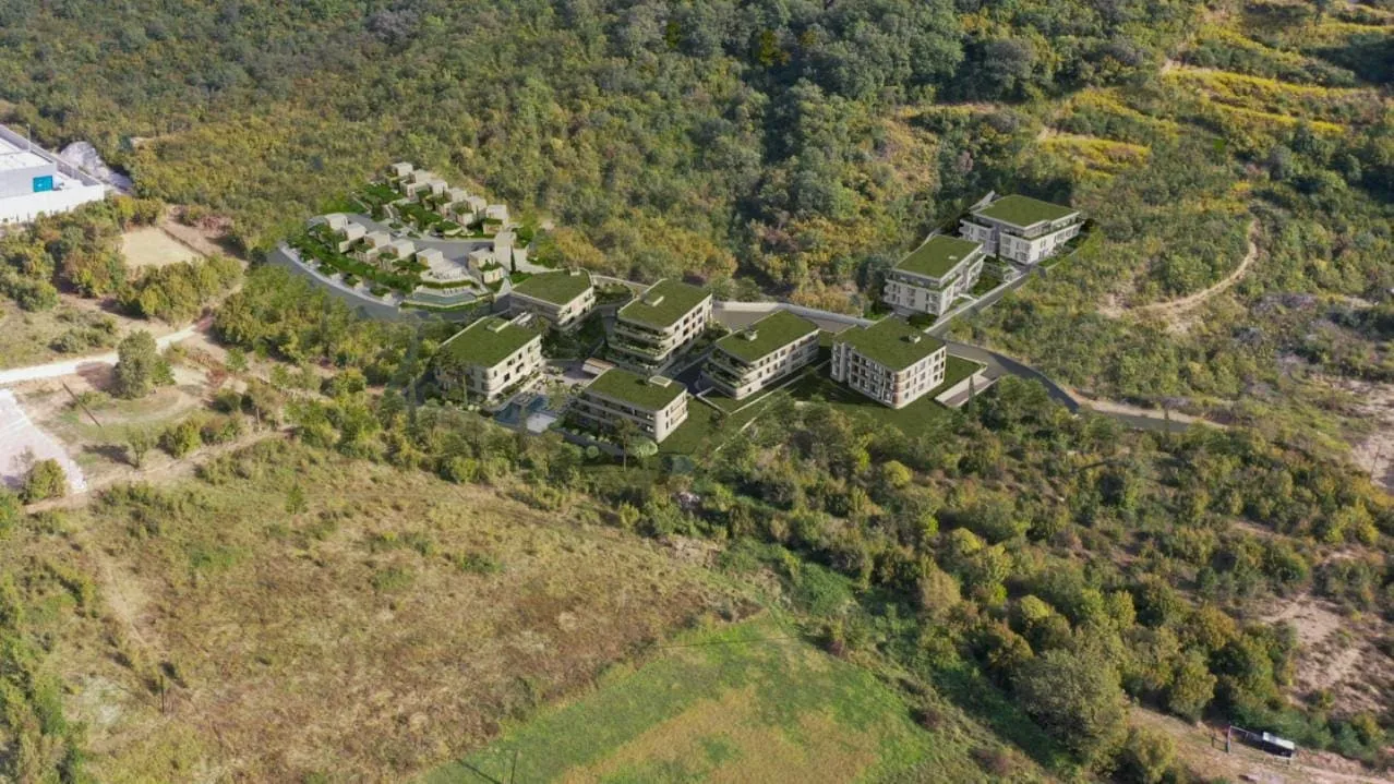 Luftaufnahme eines neuen Wohnbaukomplexes zwischen Hügeln und Grün