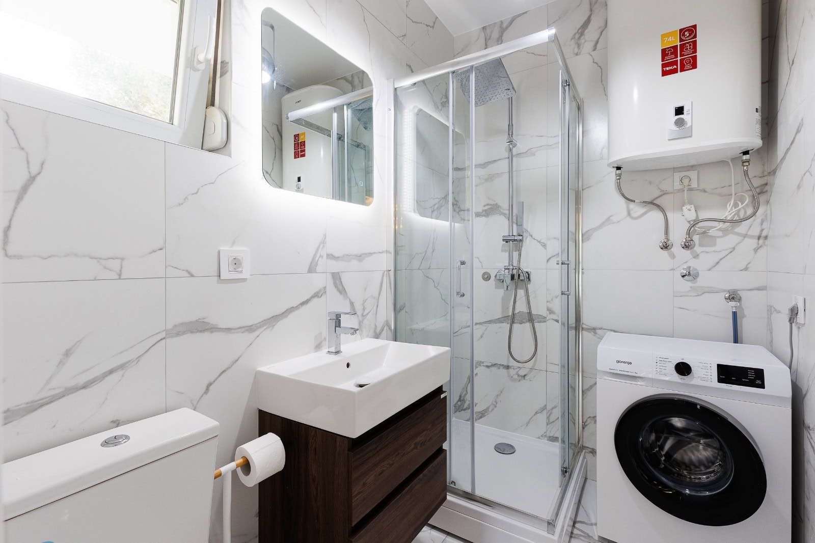 Modernes Badezimmer in einer Wohnung in Bečići, Montenegro: Duschkabine, Waschmaschine und Marmorfliesen