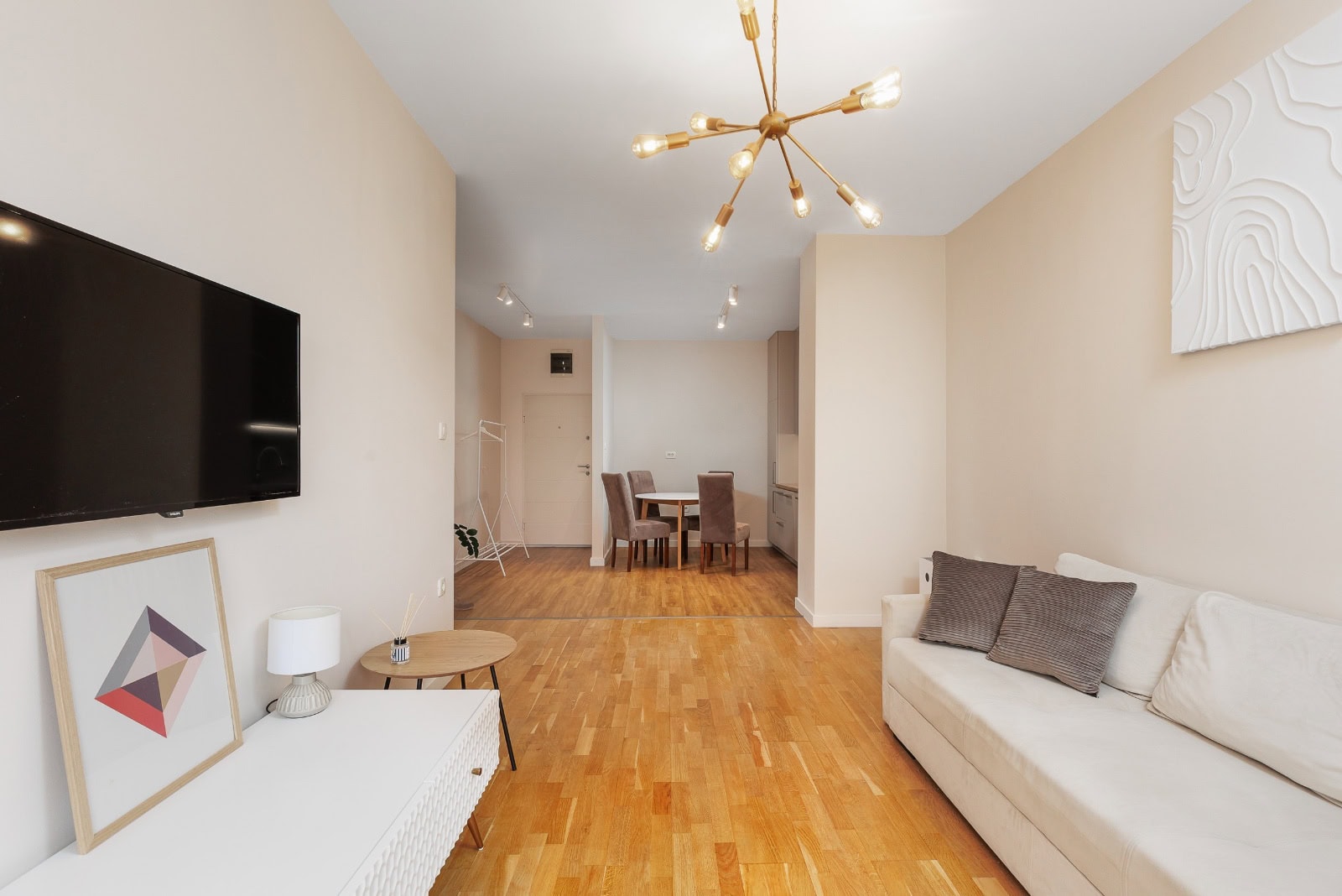 Modernes Wohnzimmer mit weißem Sofa, Fernseher und Parkett in einer Wohnung in Bečići, Montenegro