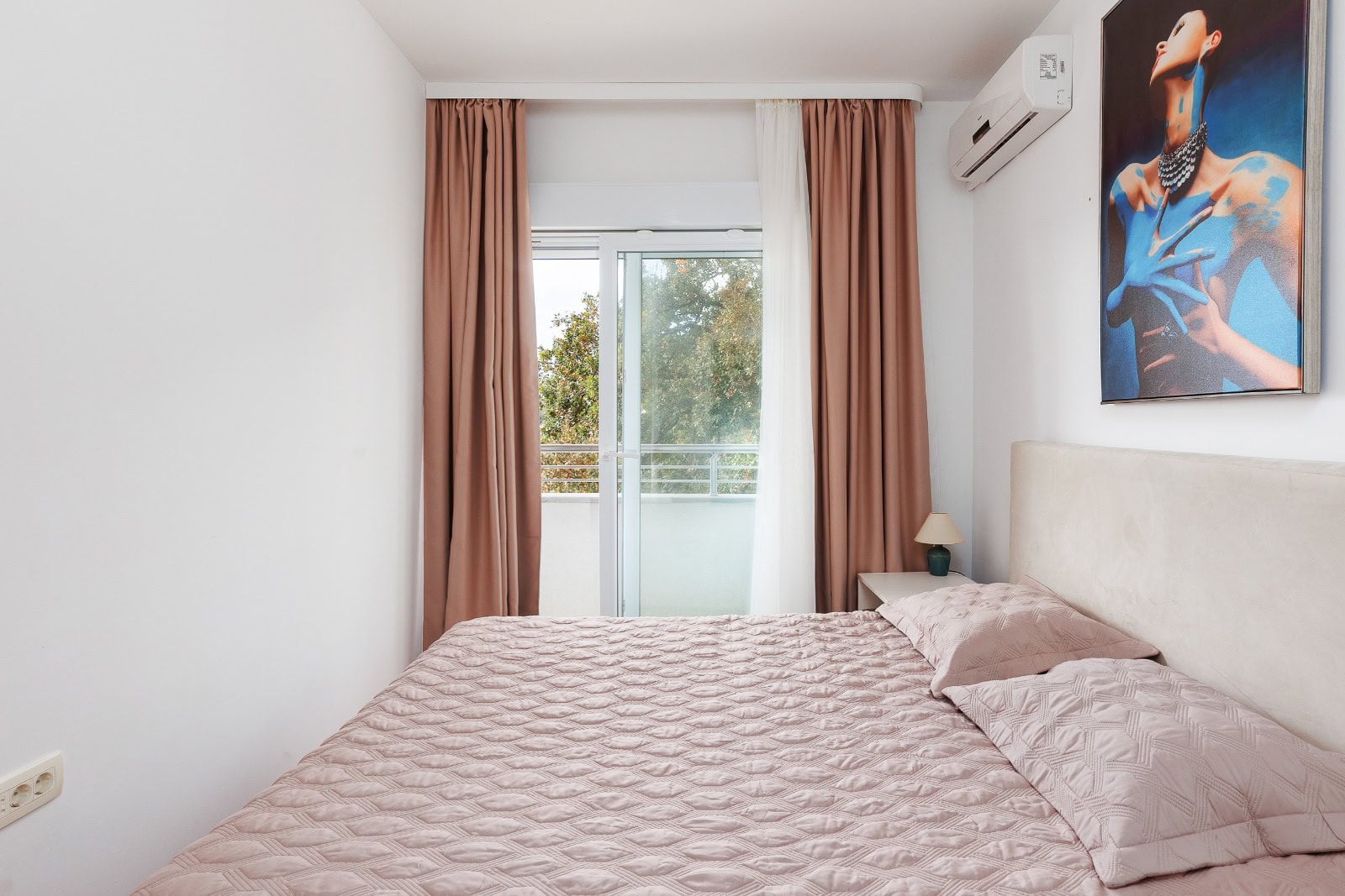 Helles Schlafzimmer mit Doppelbett und Zugang zum Balkon in einer Wohnung in Bečići, Montenegro