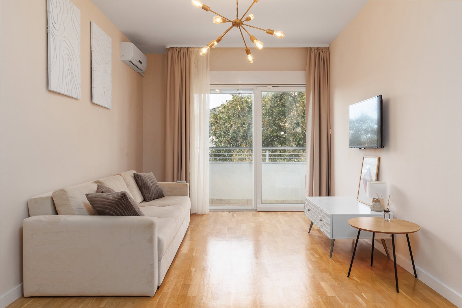 Helle Wohnzimmer mit beigem Sofa, Panoramafenster und Parkett in einer Wohnung in Bečići, Montenegro