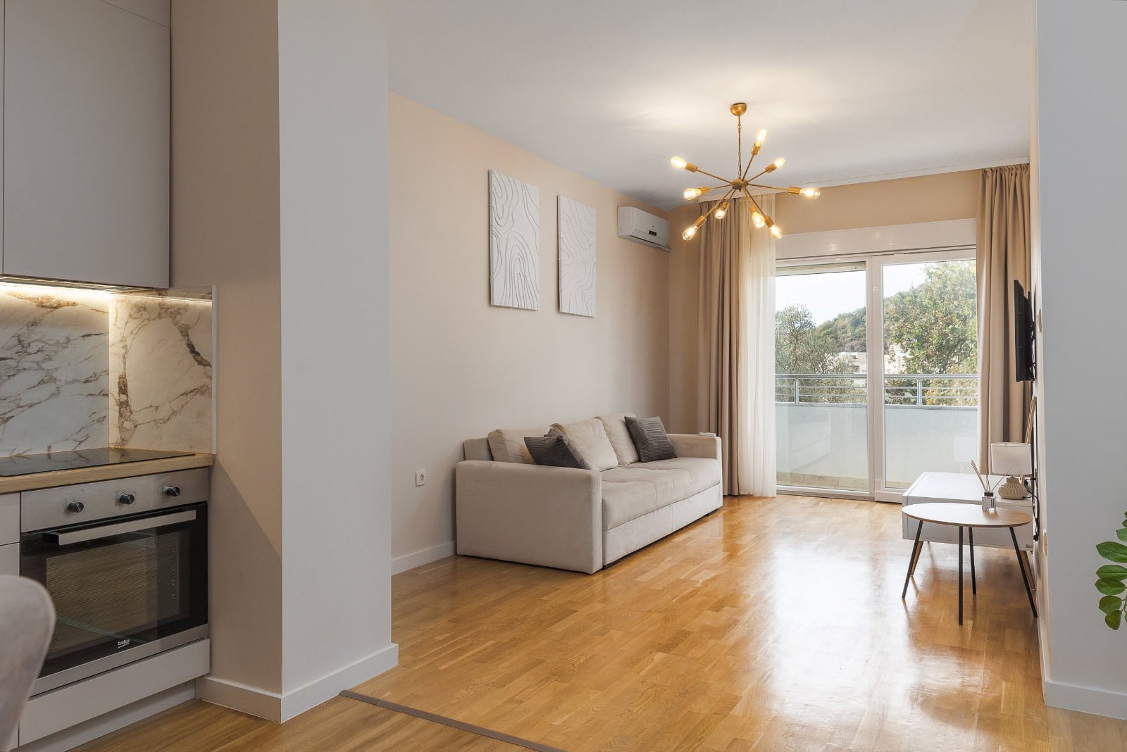 Modernes Wohnzimmer mit beigem Sofa, Küche und Zugang zum Balkon in einer Wohnung in Bečići, Montenegro
