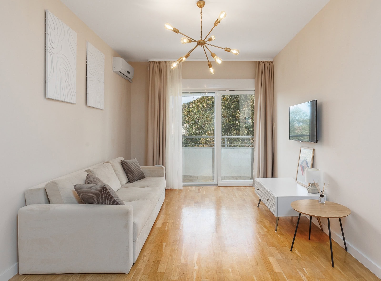 Helle Wohnzimmer mit beigem Sofa, Panoramafenster und Parkett in einer Wohnung in Bečići, Montenegro
