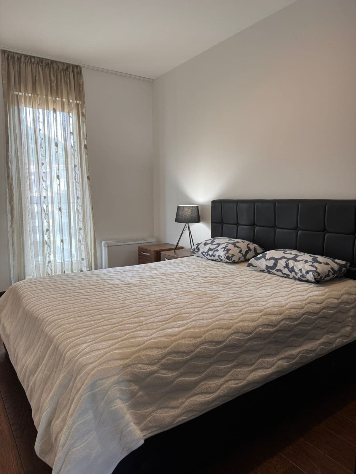 Gemütliches Schlafzimmer mit Doppelbett in einer Wohnung in Budva, Montenegro: moderne Möbel und Panoramafenster.