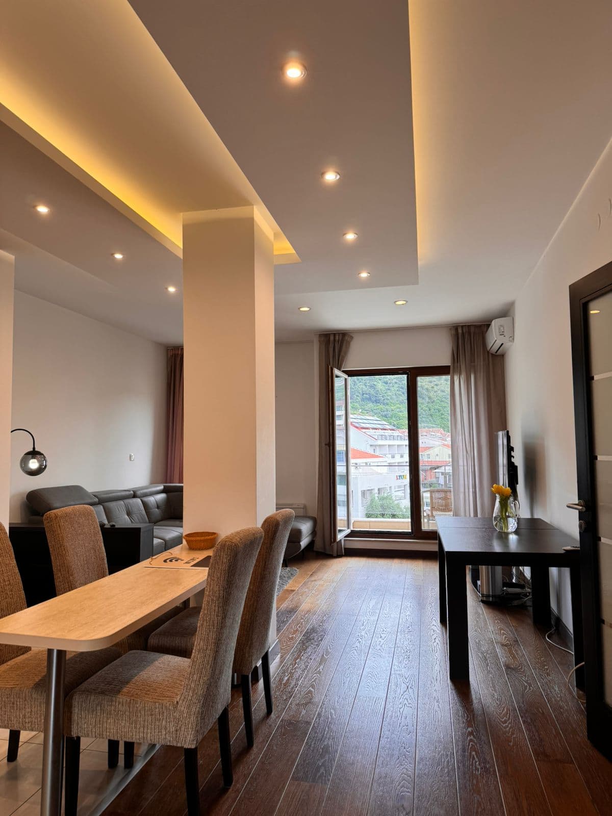Modernes Wohnzimmer in einer Wohnung in Budva, Montenegro: Essbereich, Ledersofa, Spotbeleuchtung und Bergblick.