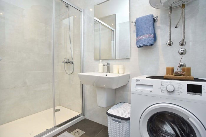 Modern bathroom in an apartment, Bečići, Montenegro: shower cabin, sink, and Beko washing machine.