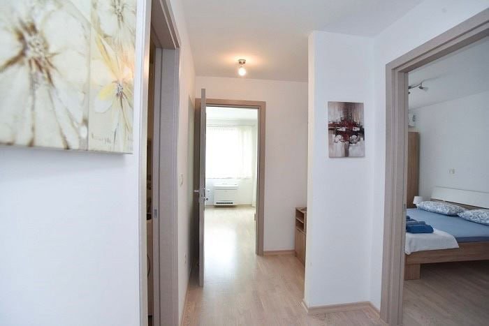 Bright hallway in an apartment in Bečići, Budva, Montenegro, with a view of the bedroom and a bright room with parquet flooring.
