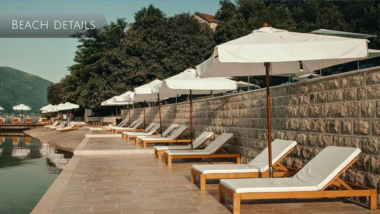 Private beach with sun loungers and umbrellas by a stone wall in Orahovac, Montenegro: seaside relaxation area.