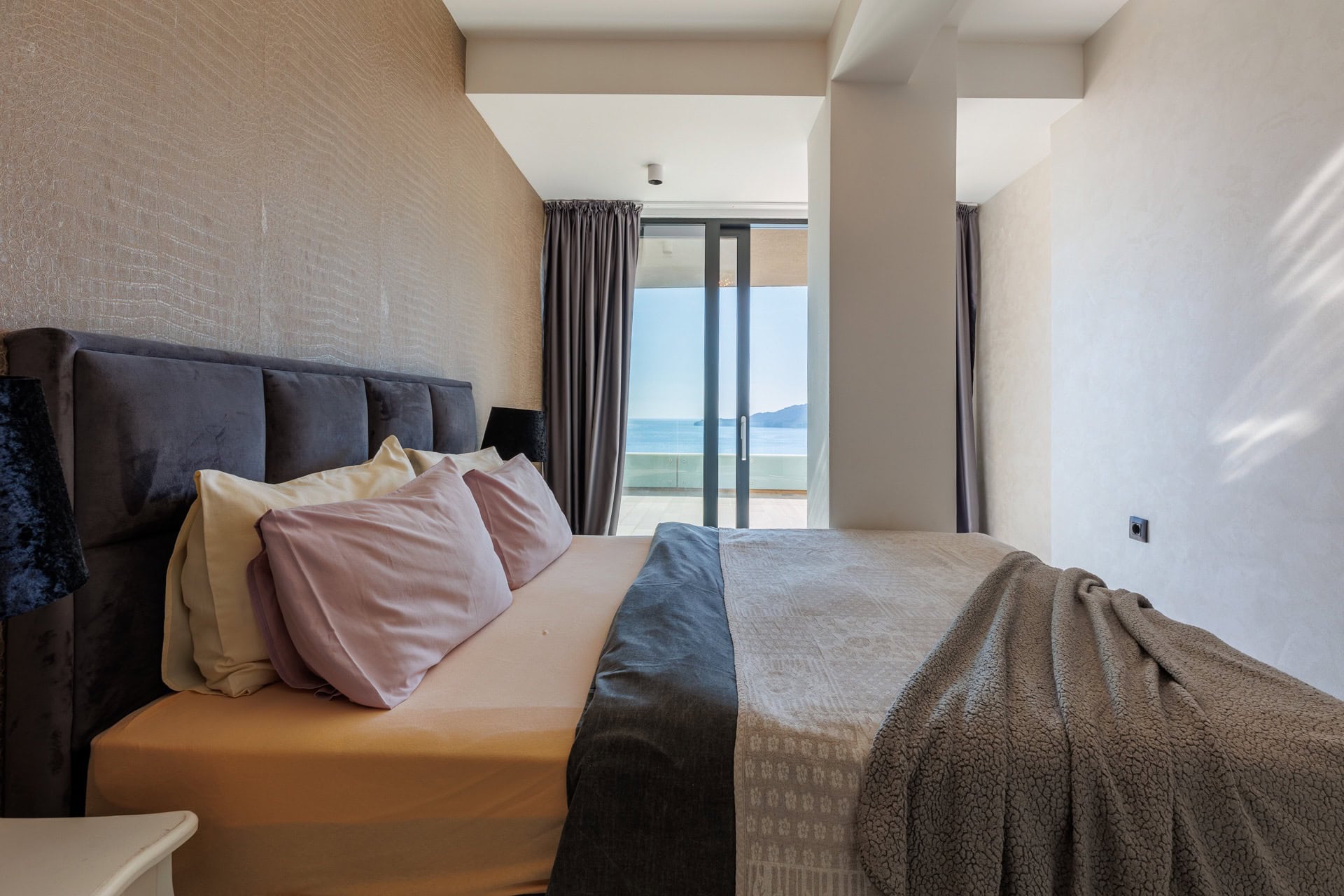 Schlafzimmer in einer modernen Wohnung in Bečići, Montenegro: Doppelbett, stilvolles Interieur und Meerblick von der Terrasse.