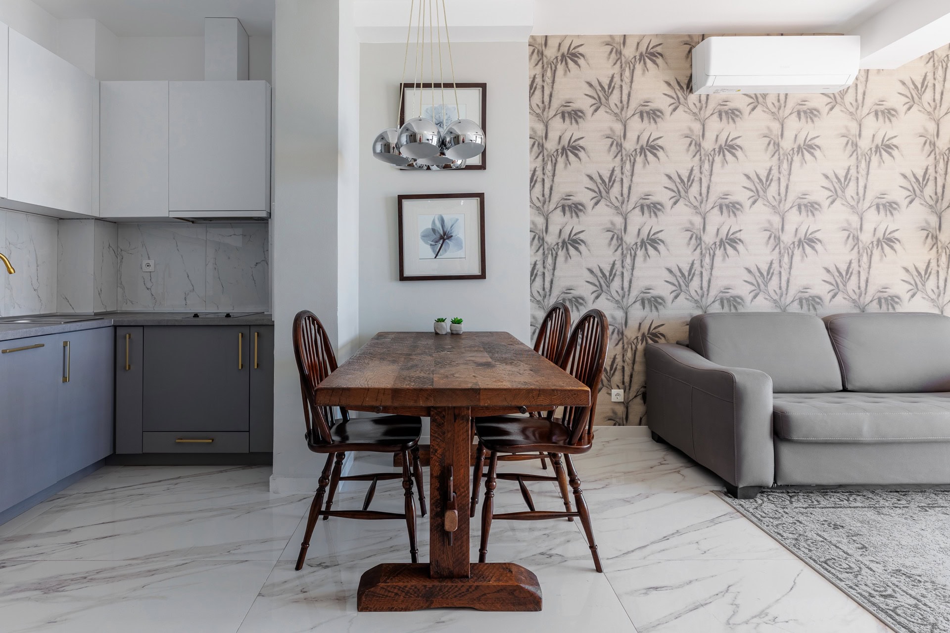 Modernes Wohnzimmer mit Küche in einer Wohnung, Bečići, Montenegro: Holzesstisch, graues Sofa und stilvolle Dekoration.