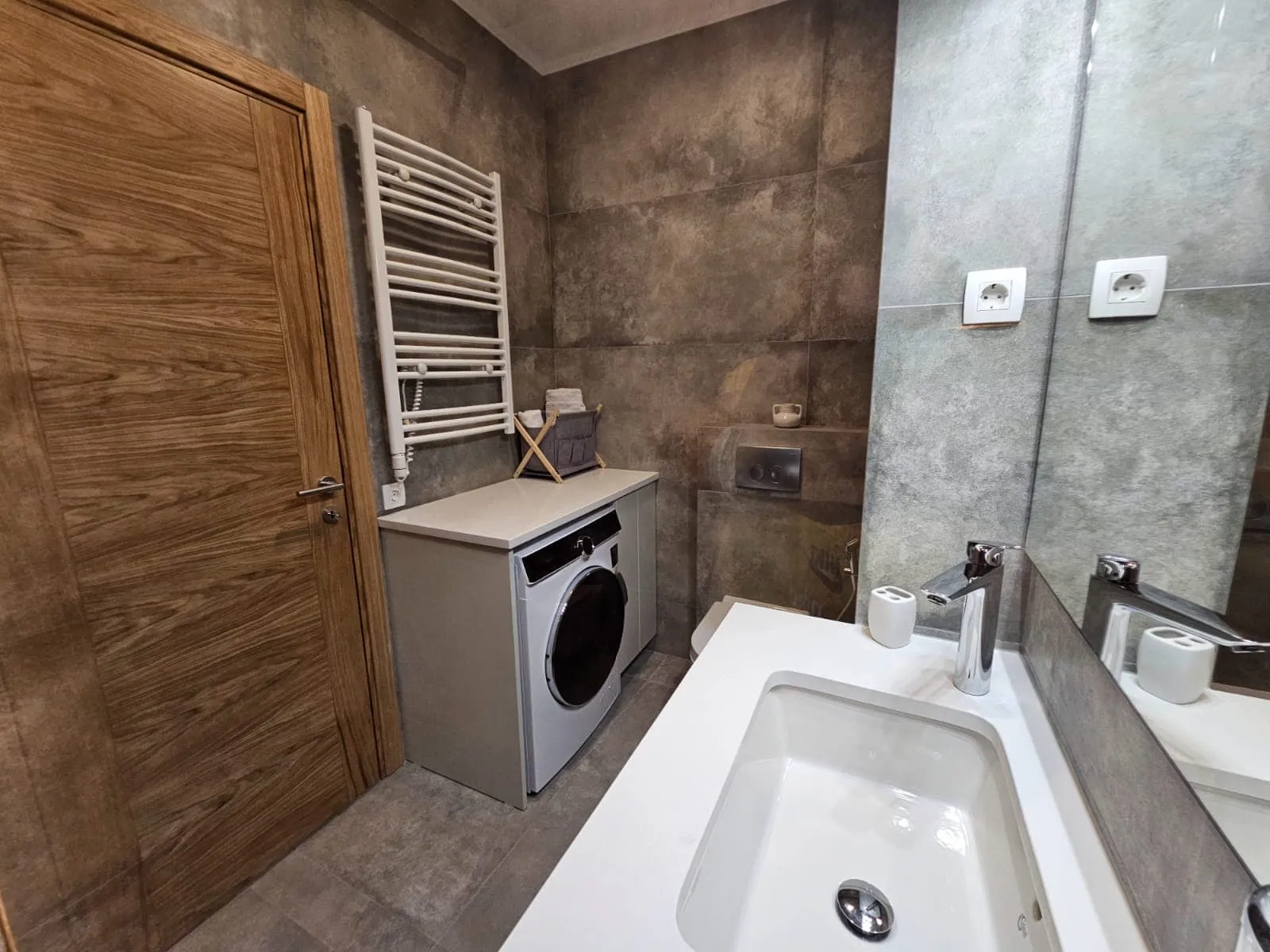 Modernes Badezimmer in einer Wohnung in Budva, Montenegro: stilvolle Ausstattung, eingebaute Waschmaschine und Waschbecken.