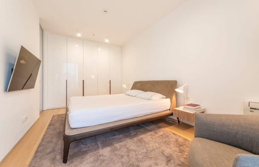 Modern bedroom in an apartment in Budva, Montenegro: double bed, built-in wardrobe, and TV in a bright interior.