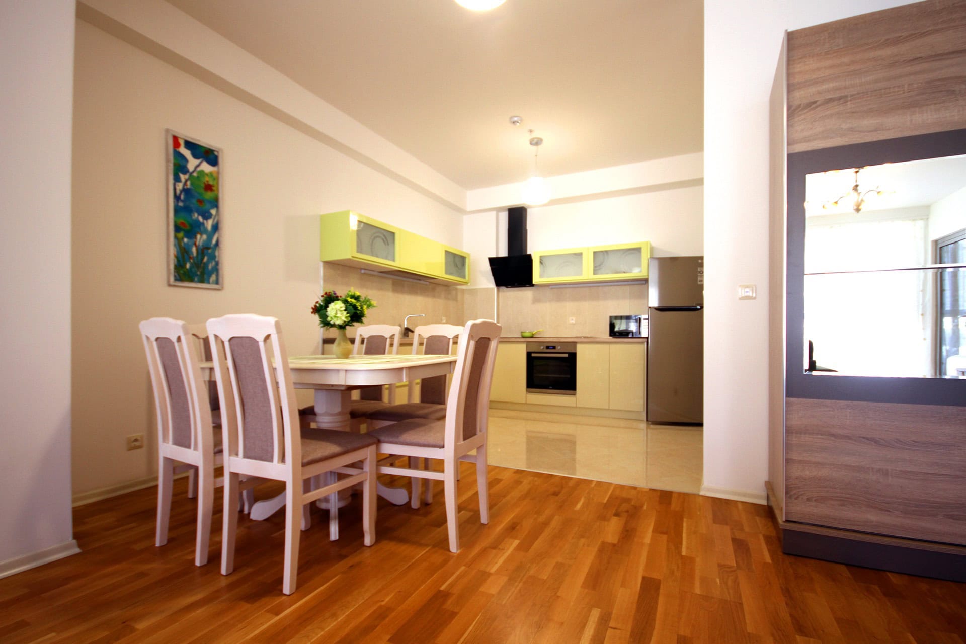 Moderne Wohnküche in einer Wohnung in Budva, Montenegro: helle Küchenzeile, Essbereich und Parkettboden.