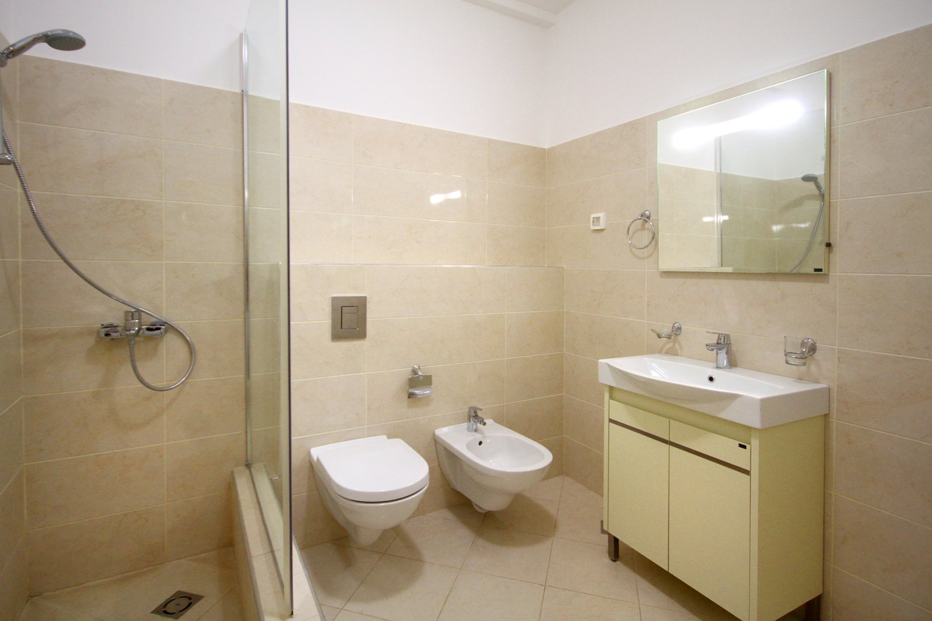 Modernes Badezimmer in einer Wohnung in Budva, Montenegro: Duschkabine, wandhängendes WC, Bidet und Waschtisch mit Waschbecken.