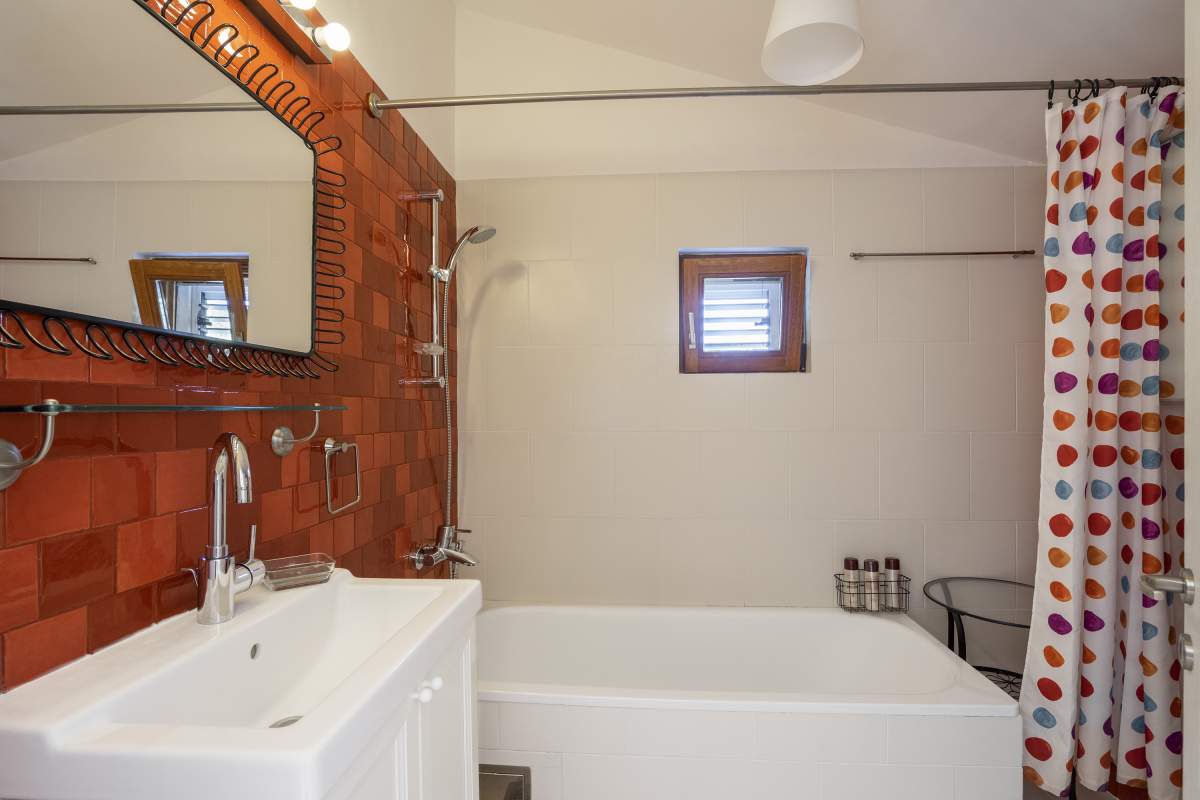 Badezimmer in einer Villa in Bigovo, Montenegro: weiße Sanitärkeramik, Terrakotta-Fliesen und ein Spiegel mit Rahmen.
