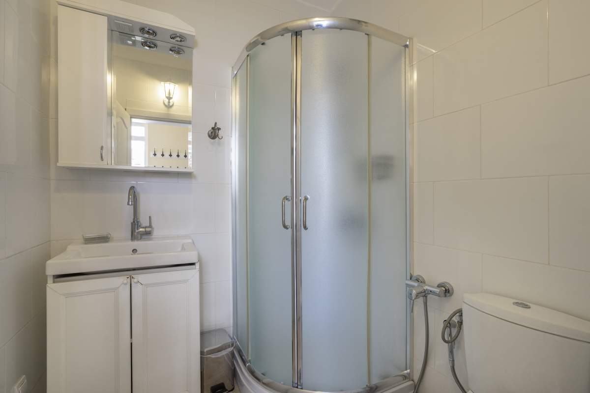 Badezimmer mit Duschkabine und weißen Möbeln in einer Villa in Bigovo, Montenegro. Modernes Badezimmerinterieur.