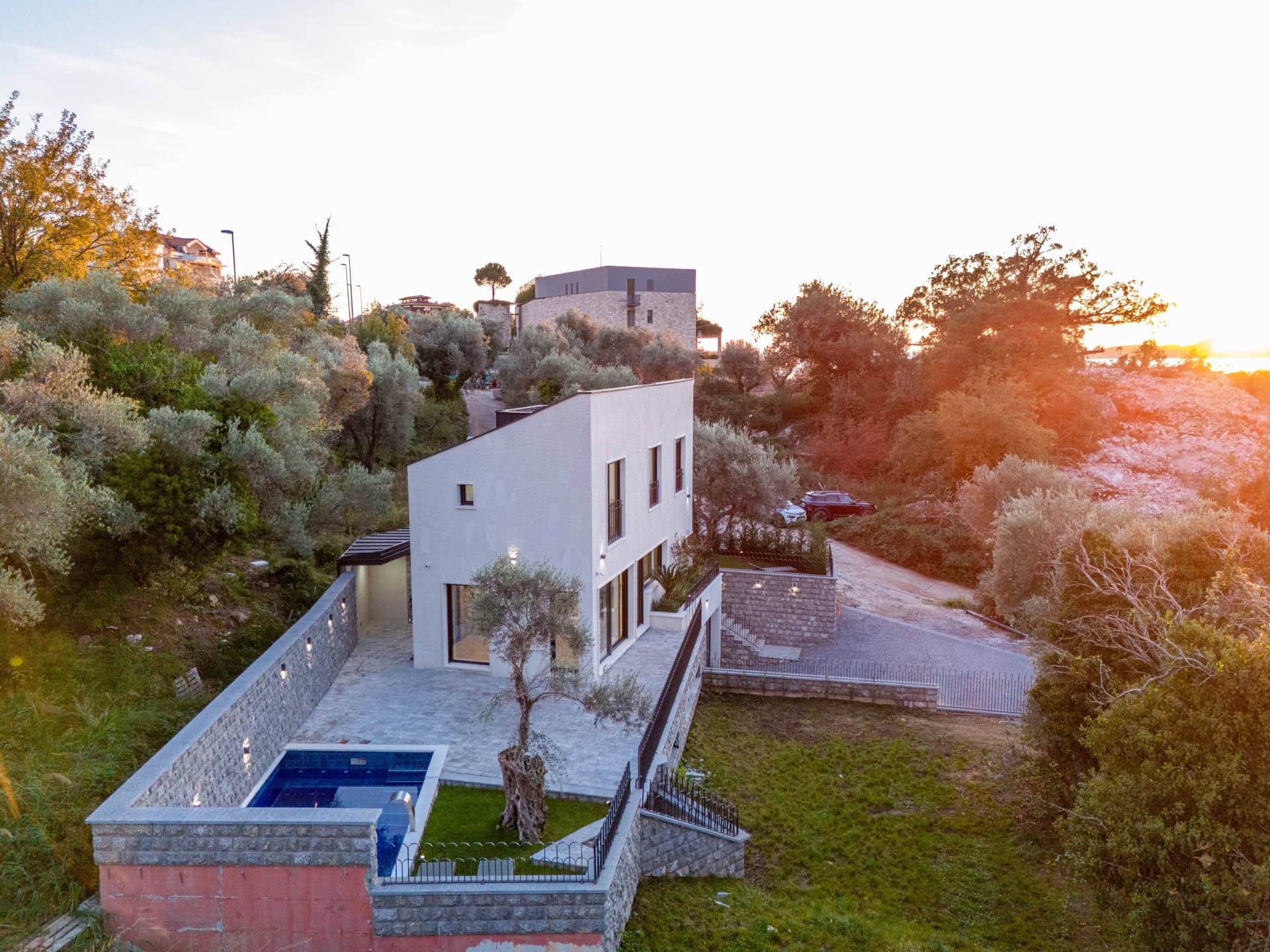 Moderne Villa mit Pool und Terrasse, umgeben von Olivenbäumen, Kamenovo, Montenegro. Luftaufnahme.